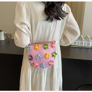 Close-up of pink hand-woven crossbody bag with colorful 3D crochet flower decorations