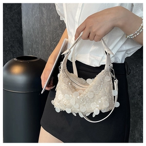 Detail view of white sequined handbag with large round discs and fine shimmering accents