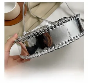 Vue rapprochée du sac argenté miroir montrant les coutures tressées et la texture métallique