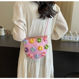 Close-up of a pink woven crossbody bag with colorful 3D crochet flower decorations