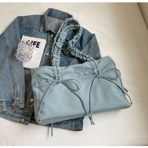 Detail van lichtblauwe nylon tas met strikaccenten en geplooide gerimpelde schouderbanden