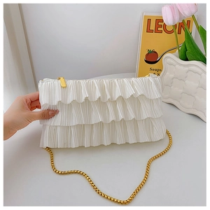 Detail of white ruffled pleats and golden snake chain strap on casual shoulder bag