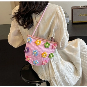 Detail of pink hand-woven shoulder bag featuring colorful crochet flower decorations