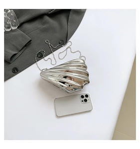 Detailed view of silver seashell evening clutch with a phone for size reference