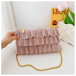 Detail of pink pleated ruffles on satin chain bag with elegant gold zipper and strap