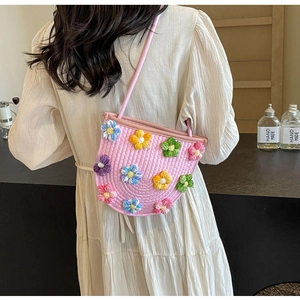 Handmade pink crochet crossbody bag featuring colorful 3D floral accents and a slim strap