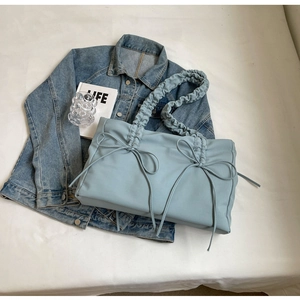 Detail van een lichtblauwe geplooide shopper met strik op een denim achtergrond