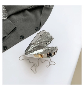 Close-up of silver shell-shaped acrylic clutch bag with metallic mirror finish and chain