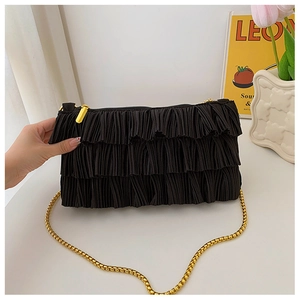 Detail of black tiered pleated fabric bag with gold chain strap and metal zipper closure