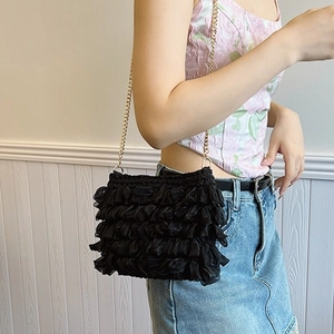 Sac bandoulière plissé en maille noire avec chaîne dorée porté par un modèle