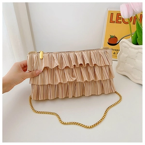 Detail of champagne gold pleated handbag with elegant layered fabric and gold chain strap