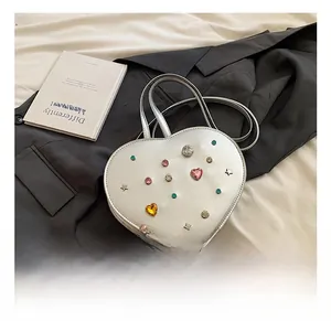 Detail of silver heart-shaped handbag with colorful gemstones and star rivets