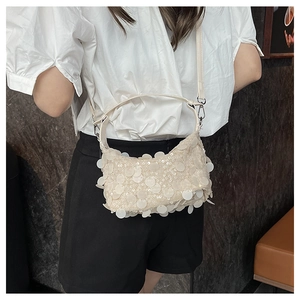Detail of cream sequin crescent bag with silver metallic hardware and adjustable strap
