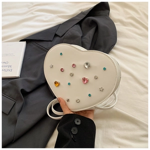 Detailed shot of white heart-shaped PU leather bag with colorful rhinestones and metal stars