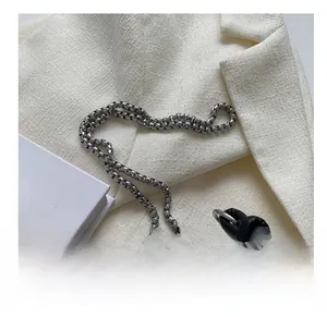 Detail shot of silver metal chain strap on black studded leather shoulder bag