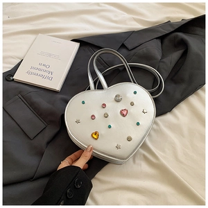 Detail of silver heart-shaped bag with colorful rhinestones and star studs on a blazer