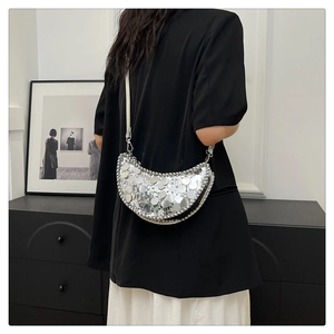 Détail d'un sac demi-lune à paillettes argentées avec bordure en chaîne métallique