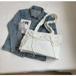 Detailopname van witte nylon shopper met geplooide handgreep en decoratieve strik