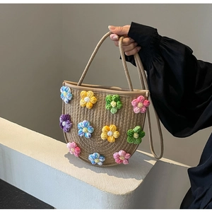 Detail of colorful crochet flower charms on a handmade straw woven crossbody bag