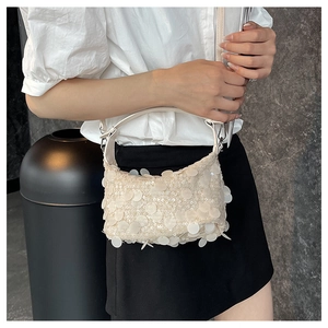 Side view of cream sequin shoulder bag with adjustable strap and metallic hardware