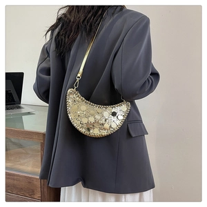 Détail d'un sac bandoulière croissant à paillettes dorées avec fine chaîne en métal