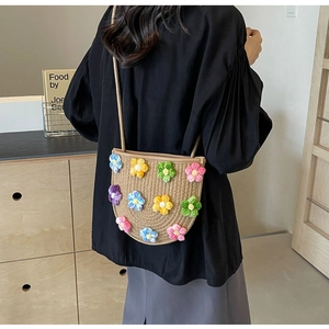 Detail of handmade woven straw crossbody bag with colorful crochet 3D flower decorations