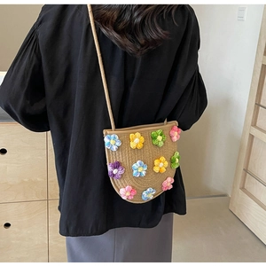 Detail of hand-woven straw crossbody bag with colorful crochet flower decorations