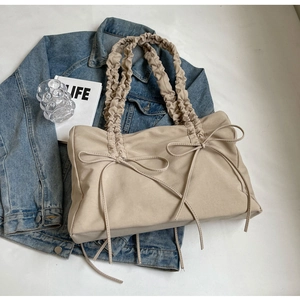 Detail van beige nylon schoudertas met strikken en geplooide riem op lifestyle achtergrond