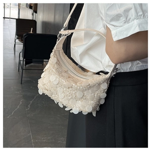 Close-up of a white sequined crossbody bag showing detailed pearl textures and silver zipper