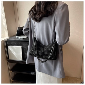 Close-up of sparkling black rhinestone handbag with thick handle and metal chain strap
