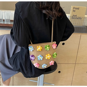 Detail of hand-woven straw crossbody bag with colorful crochet flower decorations
