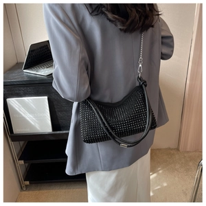 Detailed view of a black rhinestone shoulder bag on a model wearing a grey blazer