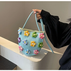 Detail of light blue hand-woven tote bag with colorful 3D crochet flowers and slim straps
