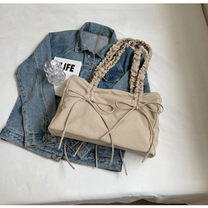 Detail van beige nylon tas met decoratieve strikken en schouderband met ruches