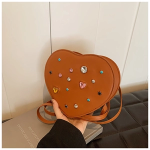 Detail of heart-shaped brown leather bag with colorful rhinestones and metal stars