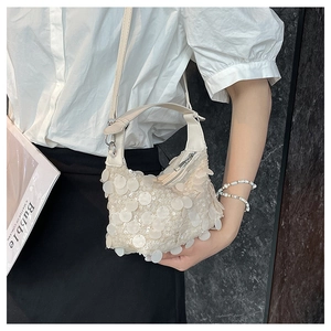 Detail shot of small creamy white handbag with large sparkling sequins and thin strap