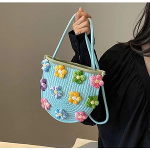 Detail of hand-crocheted light blue bag with colorful 3D floral embroidery and cord handles