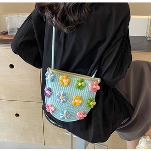 Detail of light blue woven crossbody bag with colorful crochet 3D floral accents