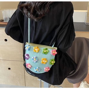 Detail of light blue woven crossbody bag featuring 3D colorful crochet flower decorations
