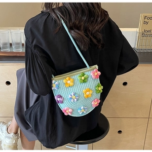 Close-up of 3D crochet flower decorations on light blue woven crossbody bag
