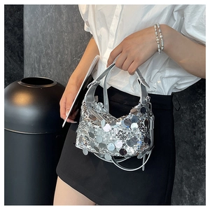 Detail of silver sequin crescent handbag with reflective discs and metallic handle