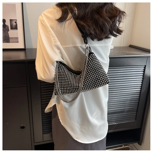 Detail of black shoulder bag with silver studs, metal chain and leather strap on a model