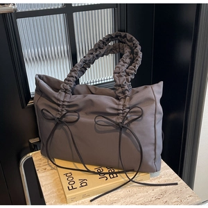 Detail van donkergrijze nylon tote tas met strikjes en geplooide wolk-handvatten