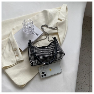 Detail of a black studded handbag with silver rivets and metal chain on a white blazer