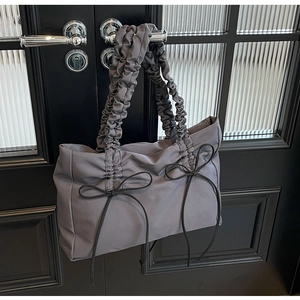 Detail van donkergrijze nylon schoudertas met geplooide banden en zwarte strikjes