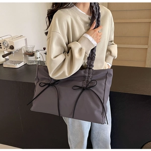 Schouderaanzicht van een nylon draagtas met strikdetails en stijlvolle plooibanden