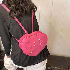 Bright pink heart-shaped mini backpack with colorful rhinestones on a female model