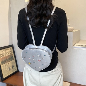Sparkling silver heart-shaped backpack with colorful rhinestones on a female model