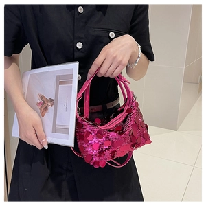Close-up of fuchsia sequin crossbody bag with metallic round discs and zipper detail