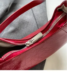 Detailed close-up of smooth silver zipper on a red leather crescent shoulder handbag